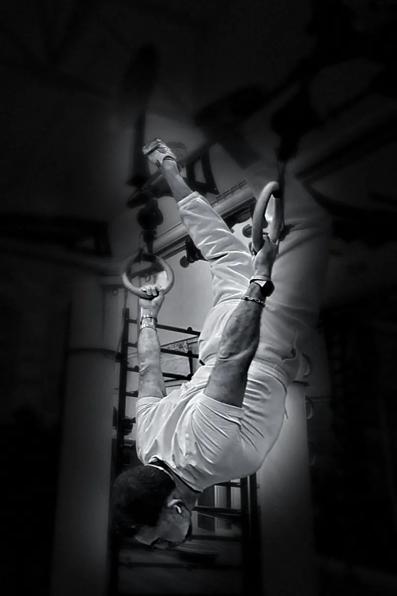 Houman Farzian upside down on gymnastic rings, black and white
