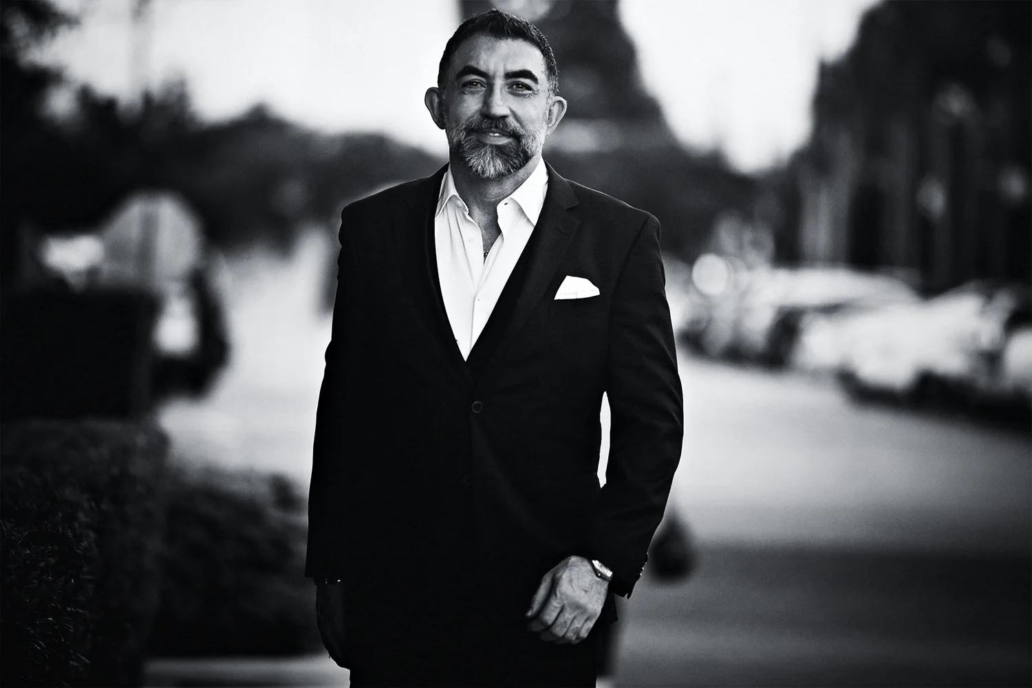 Houman Farzian walking down a Houston street in a dark suit, black and white